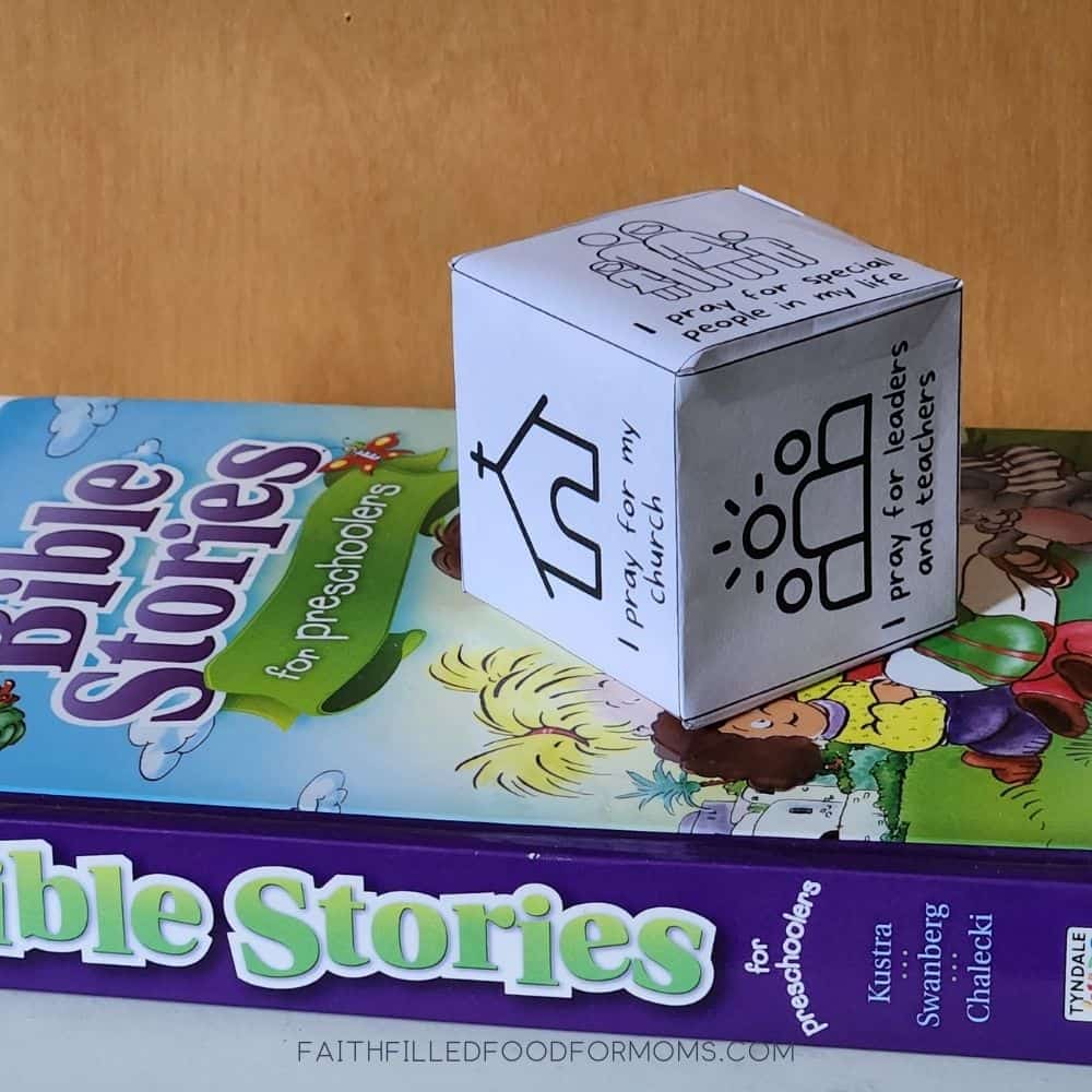 Prayer Prompts for Kids Learning How to Pray Prayer cube on top of a Bible Stories for Preschoolers book.