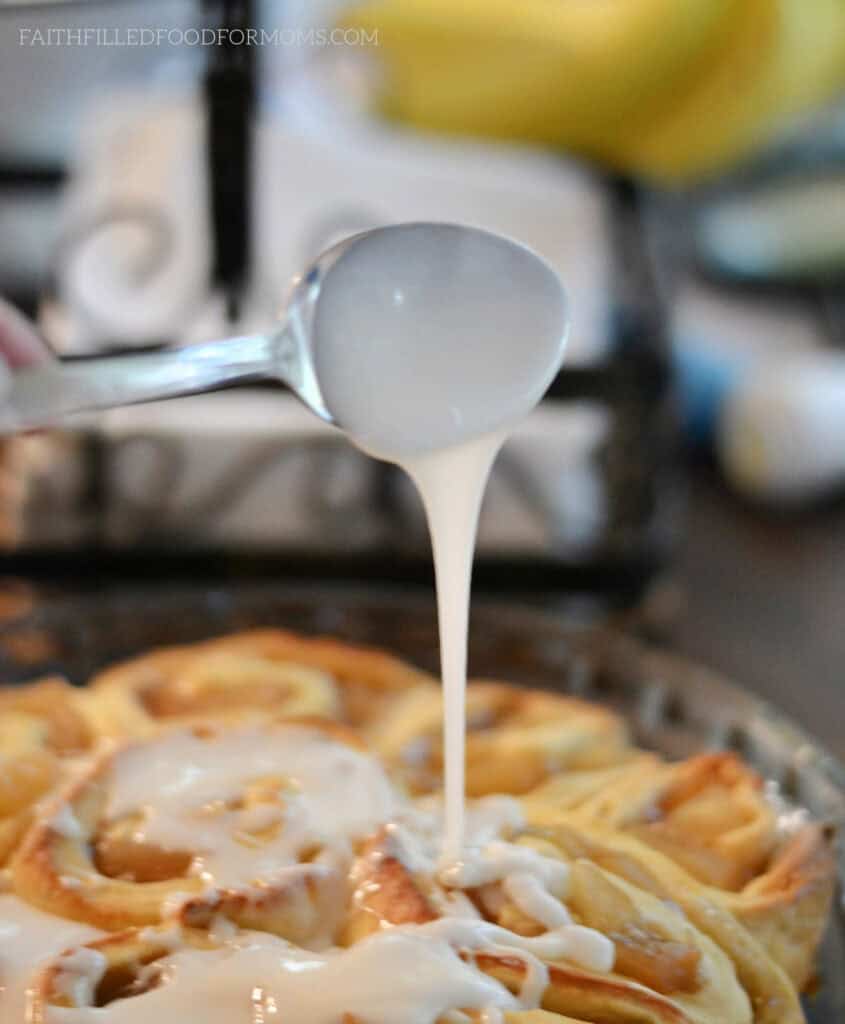 Apple Cinnamon Sweet Rolls with Icing Drizzling white vanilla icing over the golden brown Apple Cinnamon Rolls