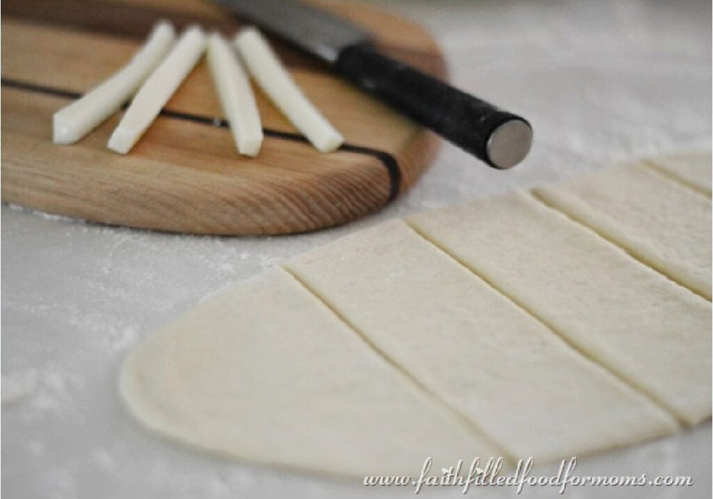 Pizza dough divided into long pieces for laying Mozzarella cheese on top