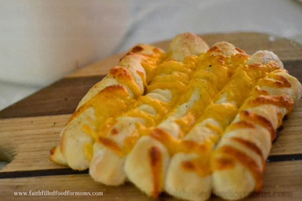 Golden brown Cheese Stuffed Breadsticks on a wood cutting board