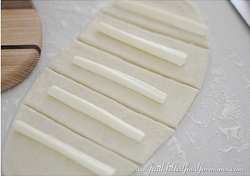 Mozzarella stick laying on homemade bread dough pieces