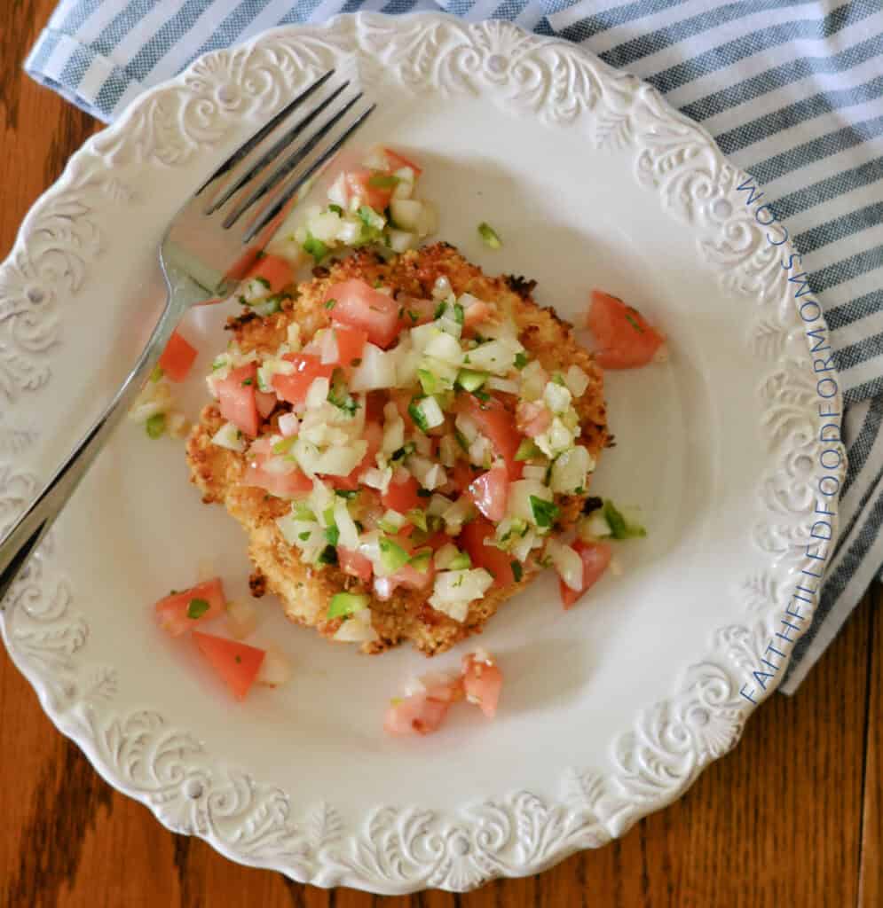 Easy Ground Chicken Patties (Crispy, 4 Ingredients & Freezer-Friendly) Homemade Chicken Patties topped with Pico De Gallo on a white plate with a fork and blue striped napkin.
