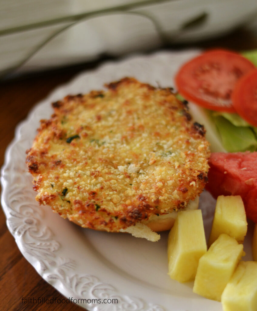 Easy Ground Chicken Patties (Crispy, 4 Ingredients & Freezer-Friendly) Chicken Patty on a bun. Pineapple beside the sandwich and lettuce, tomato and watermelon in the background