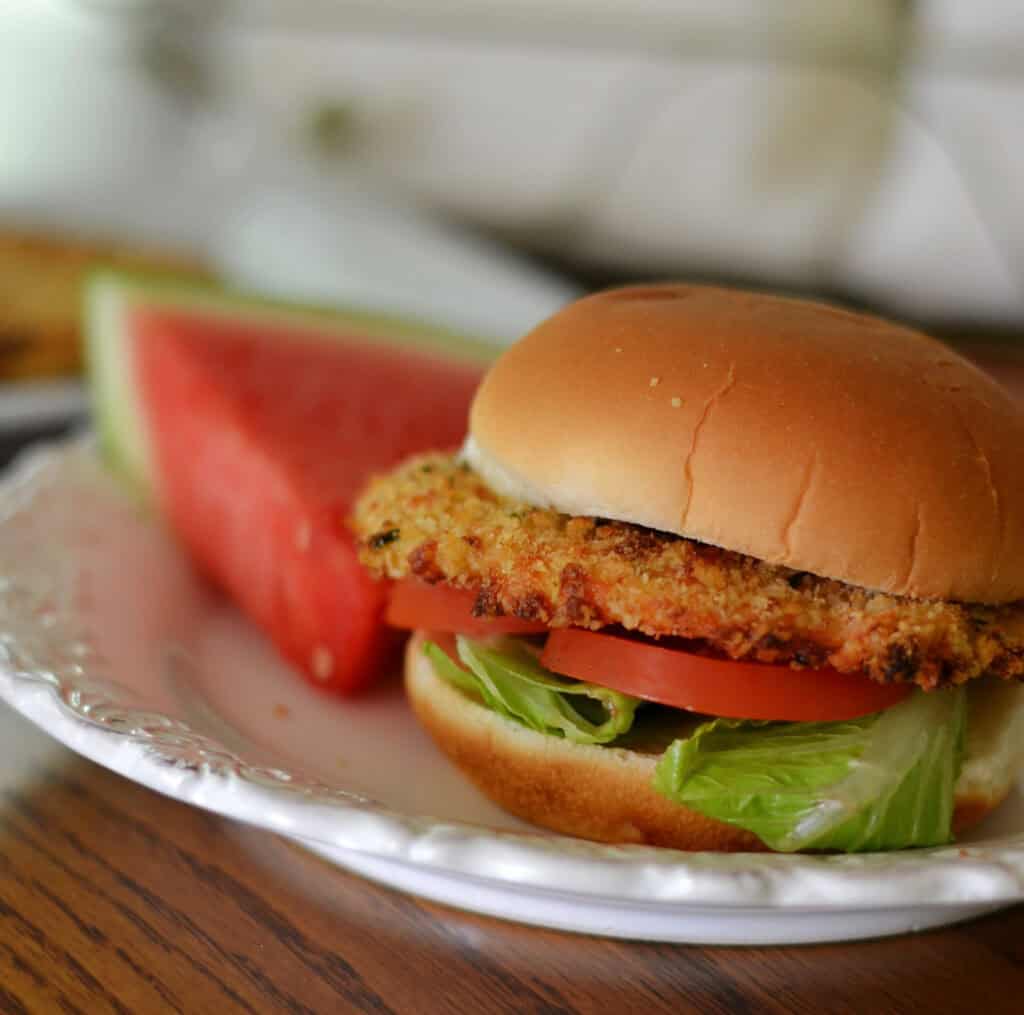 ground chicken patty recipe Crispy ground chicken burger with lettuce and tomato on a bun. Watermelon too.