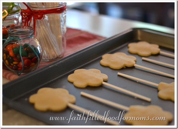 Fall Sugar Cookies Cut out sugar cookie dough on a baking sheet with candy sticks ready for baking. Cookies are shaped as sunflowers.