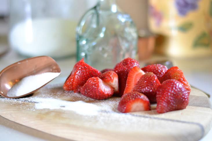 Fresh Strawberry Syrup Fresh Strawberries and sugar on a wood cutting board.