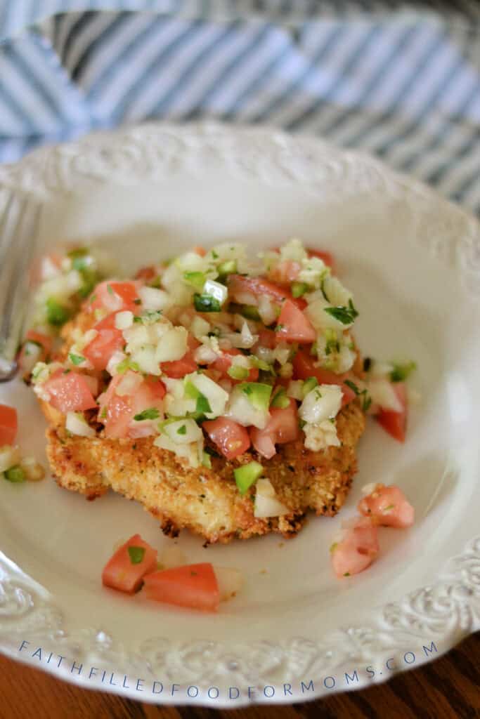 Crispy Homemade Chicken Patty on a white plate with pico de gilo on top.