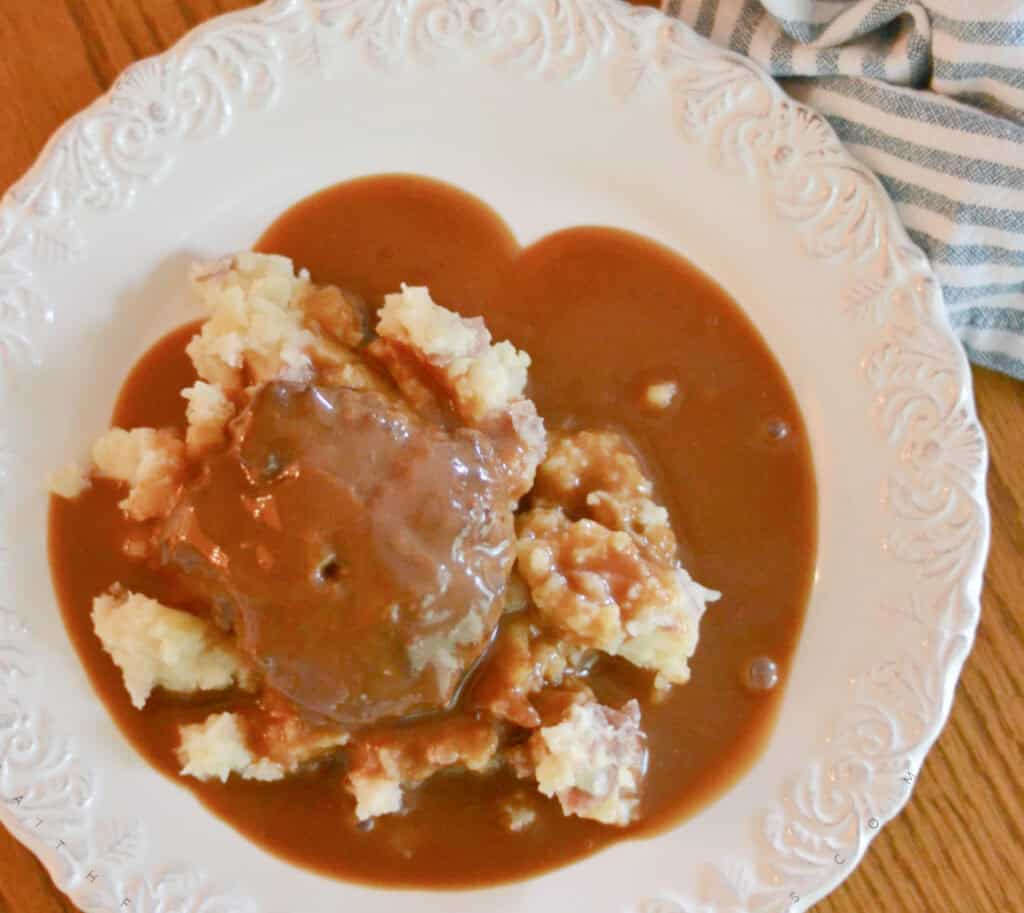 Easy hamburger steaks recipe Plated Mashed Red Potatoes and Hamburger Steak with gravy poured over the top.