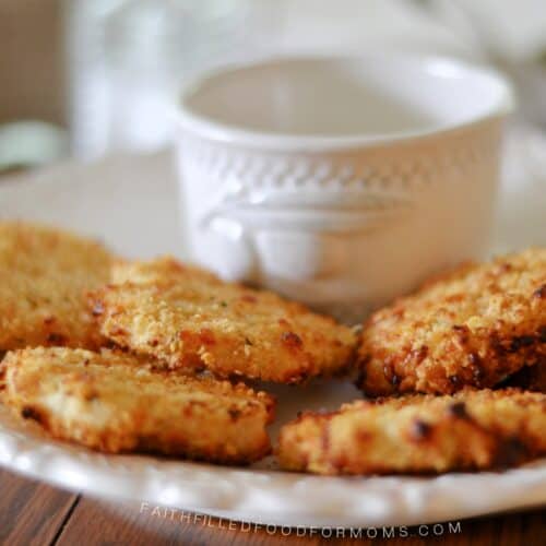Crispy Homemade ground chicken nuggets stacked on a plate with dip in the middle