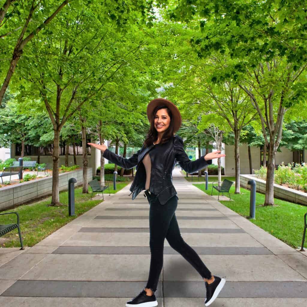 Easy ways to restore thrift store clothing Woman walking in a park with a waist high black leather jacket and hat.