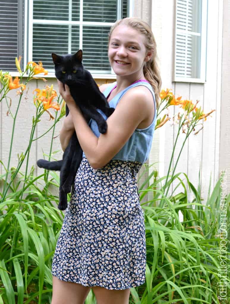 Girl holding a cat showing off her new used mended dress