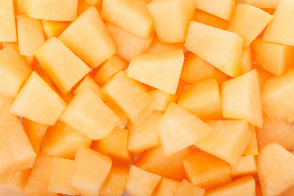 Cut up chunks of cantaloupe on a sheet pan for flash freezing.