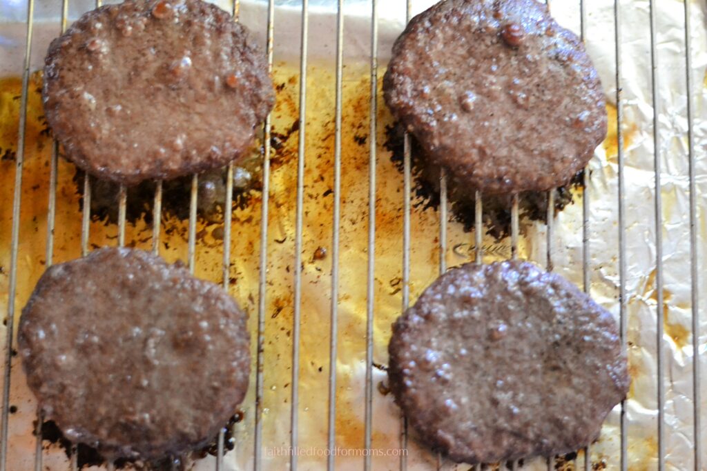 Frozen hamburgers after baking in the oven Frozen hamburgers after baking in the oven on a wire rack over a lined baking sheet.