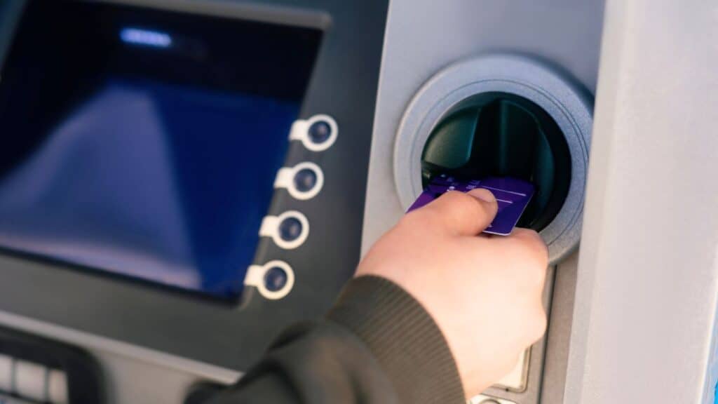 13 Essentials for Creating a Successful Year of College student inserting a debit card into a bank machine.